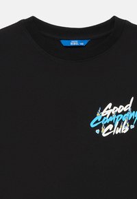 Zwarte T-shirt met een blauwe tag met de tekst "REBEL 140" en meerkleurige tekst "Good Camping Club" met vlam- en hartgraphics op de borst.