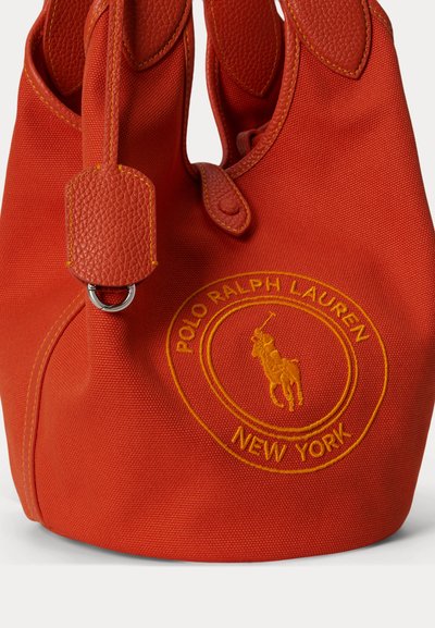 Κόκκινη υφασμάτινη τσάντα Polo Ralph Lauren με δερμάτινη επένδυση, με κεντημένο λογότυπο παίκτη πόλο και κείμενο "New York" στο μπροστινό μέρος.