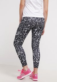 Vartalosukuvat leggingsit mustavalkoisella kuviolla, tiukasti istuva malli, valmistettu joustavasta materiaalista, yhdistettynä vaaleanpunaisiin urheilukenkiin.