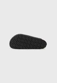 Fekete sneaker texturált szövet felsőrésszel, gumitalppal, amely hullámos mintázattal rendelkezik, lekerekített orral és minimalista dizájnnal.