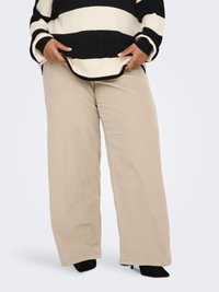 Beežikarva laiade säärega sametist püksid vertikaalsete soontega, kombineeritud must-valgete triibuliste üle suurte kampsuniga, millel on soonikkoes varrukapaelad.