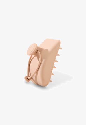 Pinza para el cabello de silicona beige con agarre en forma de corazón y dientes puntiagudos diseñada para un agarre seguro.