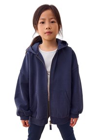 Sweat à capuche zippé bleu marine en tissu doux, avec une grande poche avant, des poignets côtelés et une capuche avec cordon de serrage.