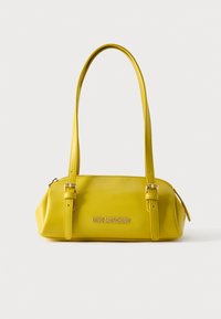 Κίτρινη τσάντα χειρός από συνθετικό δέρμα με δύο λουριά για τον ώμο, ορθογώνιο σχήμα, επιχρυσωμένες μεταλλικές λεπτομέρειες και ανάγλυφο λογότυπο στο μπροστινό μέρος.