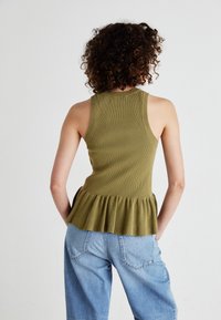 Olive rohelise soonikuga tank-top peplumäärisega, koos helesiniste laienevate teksadega. Topil on sobiv kehakuju ja ümar seljataga.