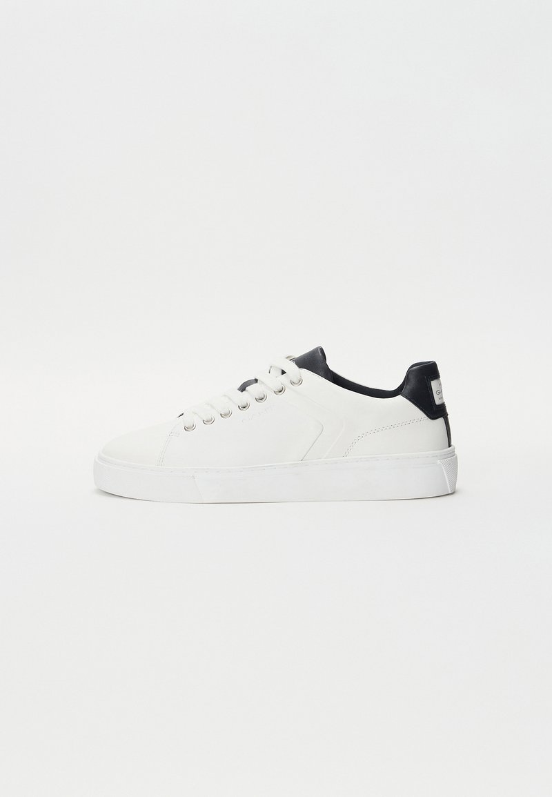 Adidași albi cu un exterior din piele netedă, accent de călcâi negru, vârf rotund și design cu șireturi. Talpă groasă albă cu model texturat.