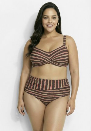 Smiling woman with long dark hair wears a brown striped bikini with high-waisted bottoms, standing against a plain light background.
