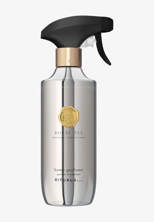 Botella de spray de vidrio transparente con un gatillo negro mate, acentos metálicos dorados y una etiqueta que presenta el texto "Royal Tea" y "perfume para el hogar".