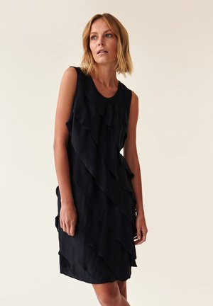 Robe noire sans manches avec un design à volants en plusieurs couches. Fabriquée en tissu léger, elle présente un col rond et une coupe décontractée.