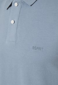 Polo bleu clair avec deux boutons blancs et logo Esprit brodé sur la poitrine.