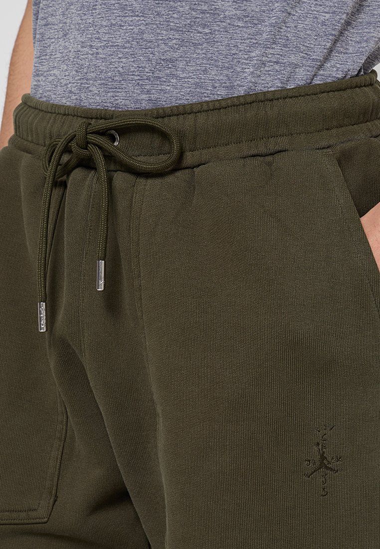 Pantalones jogger verdes oliva con cintura con cordón, que presentan una tela texturizada y un logo discreto bordado en la parte inferior de la pierna.