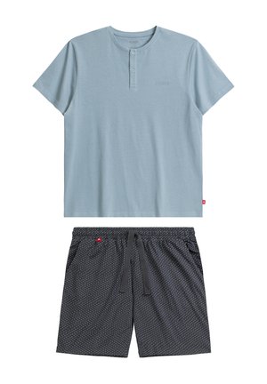 Jasnoniebieski bawełniany t-shirt z trzema guzikami; w połączeniu z czarnymi szortami w białe kropki i regulowanym sznurkiem.