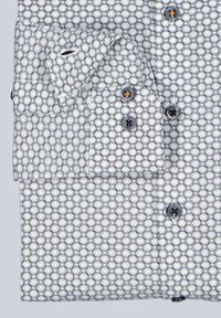 White dress shirt with blue circular pattern, dark buttons, and folded sleeves against a light background.
