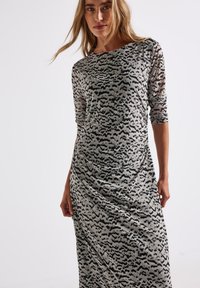 Graues Kleid mit schwarzem abstraktem Muster, langen Ärmeln und rundem Halsausschnitt. Hergestellt aus strukturiertem, leichtem Stoff; tailliertes Design mit Drapierungselementen.