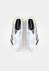 White athletic shoes with black striped accents, sleek design, textured surface, and prominent "Predator" branding on the tongue.