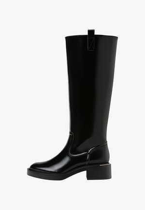 Črne hlačne škornje do kolen z sijočo površino, zaobljenim nosom, majhnim blokastim petom in zanko za poteg na hrbtni strani. Šivi poudarjajo obliko.