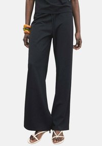 Black wide-leg pants made of soft fabric with an elastic waistband and drawstring. No visible patterns or hardware details.