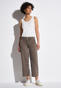 Top de tirantes gris claro con escote redondo, combinado con pantalones cortos sueltos color topo que cuentan con bolsillos frontales y dos botones en la cintura.