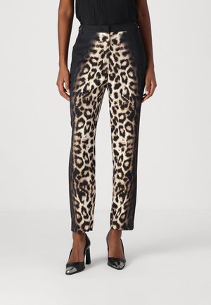 Leopardenmuster-Hose aus glattem Stoff, mit schmalem Schnitt und kontrastierenden schwarzen Seiten. Kombiniert mit schwarzen High-Heels.