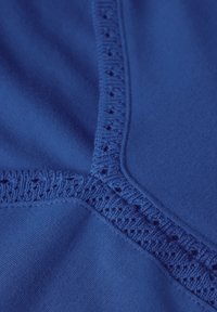 Tejido azul con una textura suave que presenta un borde decorativo de encaje a lo largo de la costura. El cuerpo principal es de un azul sólido y vibrante.