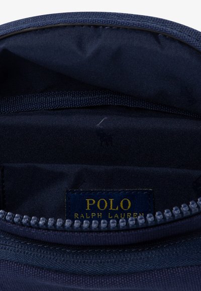 Marinblå tygpås med dragkedja, med en gold "POLO RALPH LAUREN"-tagg och ett subtilt logomönster inuti. Hållbar textilstruktur.