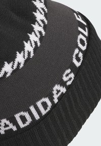 Beanie nera a maglia con testo bianco "ADIDAS GOLF" e motivo a zigzag in contrasto. Texture a coste sull'orlo. Materiale morbido.