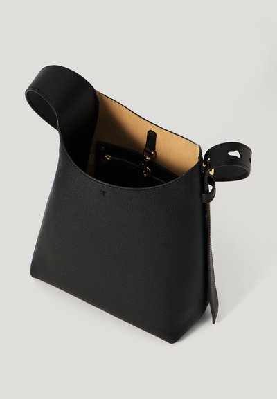 Black leather handbag with a textured surface, open top, and a detachable, perforated strap. Interior features a zip pocket.