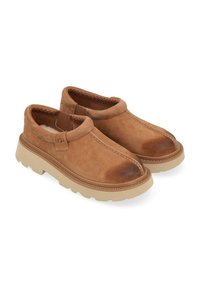 Scarpe slip-on in suede marrone con punta rotonda, interno imbottito, suola in gomma e dettagli a cucitura a contrasto lungo i bordi.