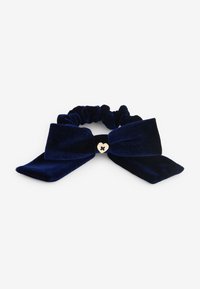 Scrunchie in velluto blu navy con due grandi fiocchi piatti e un accento a forma di cuore dorato al centro. Texture morbida, colore ricco e design elegante.