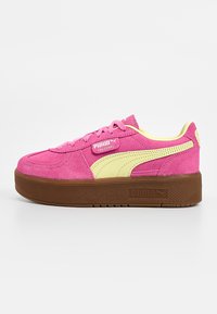 Baskets Puma Palermo en daim rose avec bande jaune, semelle plateforme marron et lacets roses, vues de profil extérieur sur fond blanc.