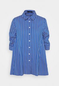 Camicia a righe blu e bianche con colletto, chiusura a bottoni e maniche tre quarti; silhouette svasata con una texture di tessuto morbido.