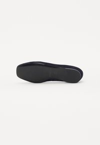 Semelle en suede bleu marine avec une semelle en caoutchouc lisse et texturée pour une meilleure adhérence, et un design de bout arrondi.