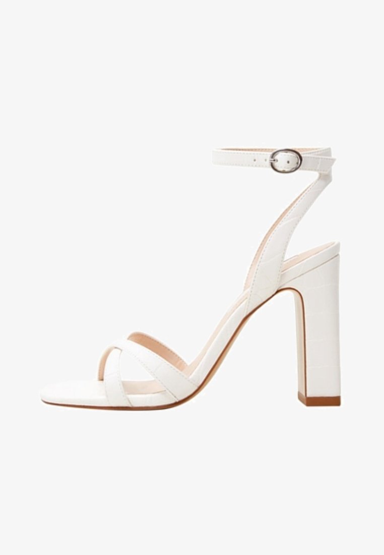 Sandale blanche à talon haut avec bride à la cheville, fermeture à boucle et deux brides avant sur les orteils ouverts, avec un design à talon bloc.