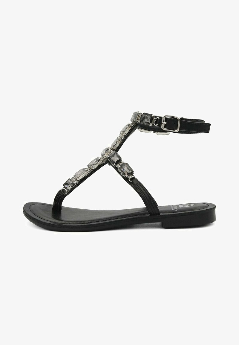 Infradito neri piatti con design a T-strap. La parte superiore presenta dettagli trasparenti e sfaccettati, e una cinturino alla caviglia con fibbia. Suola liscia.