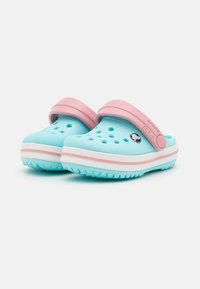 Light blue clogs with a pink strap, featuring ventilation holes, white and pink accent stripes, and textured soles for grip.