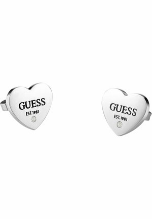 Paar zilveren oorstekers in hartvorm met "GUESS EST. 1981" gegraveerd en een kleine ronde kristal onder de tekst.