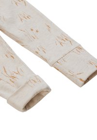 Lichtbeige katoenen broeken met een tarwepatroon in zacht oranje. De boorden zijn geribbeld en de stof lijkt zacht en textuur te hebben.
