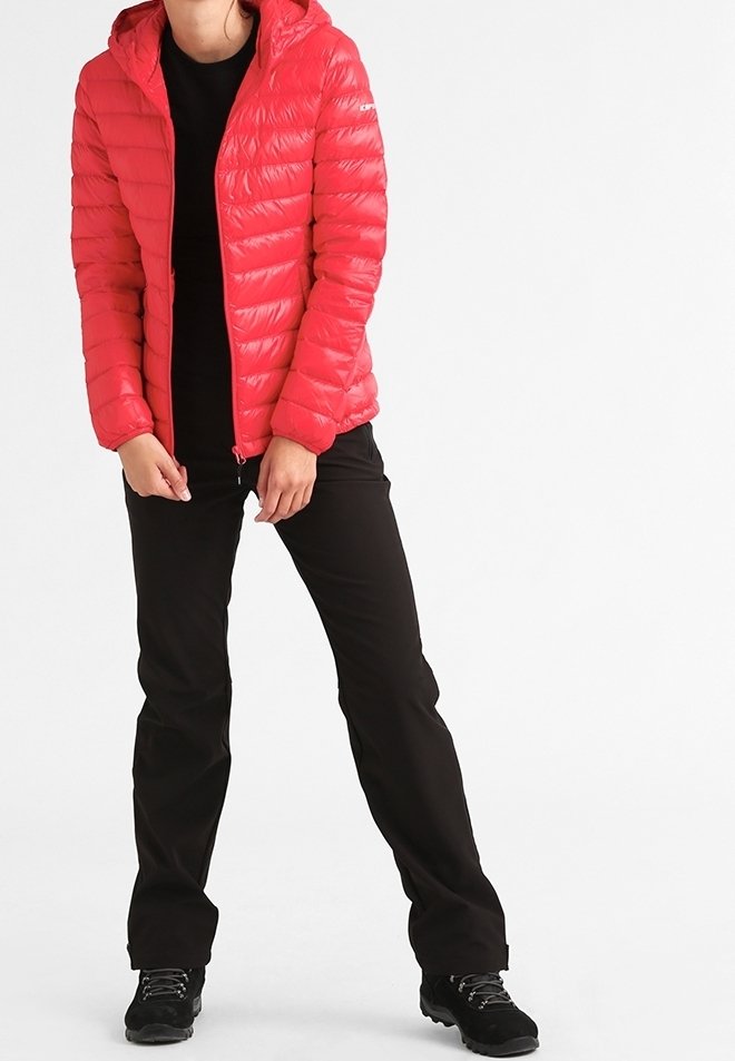 Personne portant une veste matelassée rouge vif, un pantalon noir et des chaussures de randonnée noires, debout les jambes écartées sur un fond blanc.