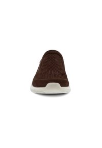 Brown slip-on shoe with a textured mesh upper and a white rubber sole. Features a rounded toe and minimalistic design.