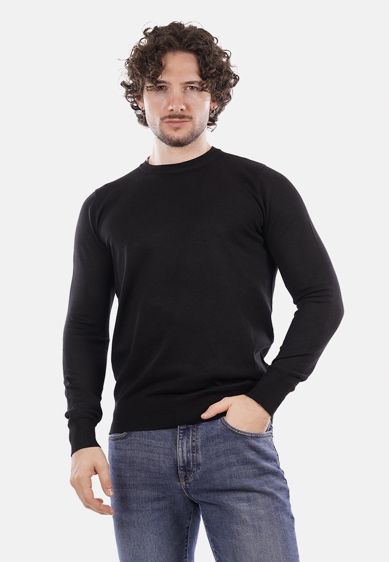 Maglione nero lavorato a maglia con maniche lunghe e scollatura rotonda, abbinato a jeans blu, con polsini e orlo a coste.