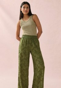 Khaki zelené široké kalhoty s květinovým vzorem, spárované s přiléhavým, strukturovaným zlatým tílkem. Uvolněný střih s elastickým pasem.