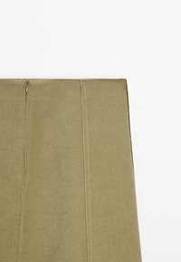 Jupe en tissu kaki à texture lisse, présentant une couture verticale et une fermeture éclair discrète à l'arrière. Design simple et droit.