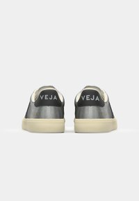 Sneaker nere e argento con finitura in pelle liscia, caratterizzate da un profilo basso, suole chiare e logo impresso sul retro.