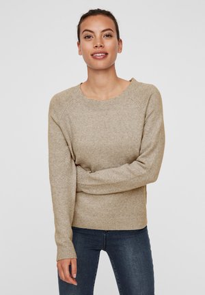 Beige gebreide trui met een ronde halslijn en raglanmouwen. Zachte textuur, geribde manchetten en onderrand, gecombineerd met donkere jeans.