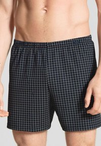Boxers pour hommes bleu marine avec un motif floral blanc sur l'ensemble, taille élastique et tissu léger et respirant.
