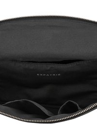 Intérieur de la pochette noire zippée avec un séparateur en tissu et le nom de la marque "Expatrié" imprimé en blanc à l'intérieur.