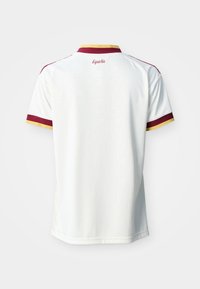 Balta īss piedurkņu sporta krekls ar sarkanu un dzeltenu apdari apkaklē un piedurknēs, uzraksts "España" centrēts zem apkakles uz muguras.