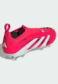 Scarpette da calcio rosse con tomaia testurizzata, righe bianche e suola argento. Presenta un anello sul retro per facilitare la calzata.