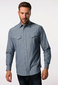 Dlouhá denimová košile, světle modrá, zapínání na knoflíky s dvěma náprsními kapsami, špičatý límec a jemná textura. Obsahuje kovové cvokové knoflíky.