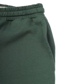 Gröna sweatpants med elastisk midja, mjuk textur och detaljer i sidan, som visar ett slätt trikåtyg.